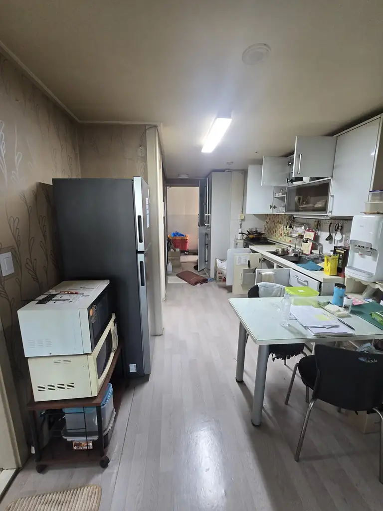 정리 전 냉장고 식탁 전자레인지와 생활용품이 놓인 주방